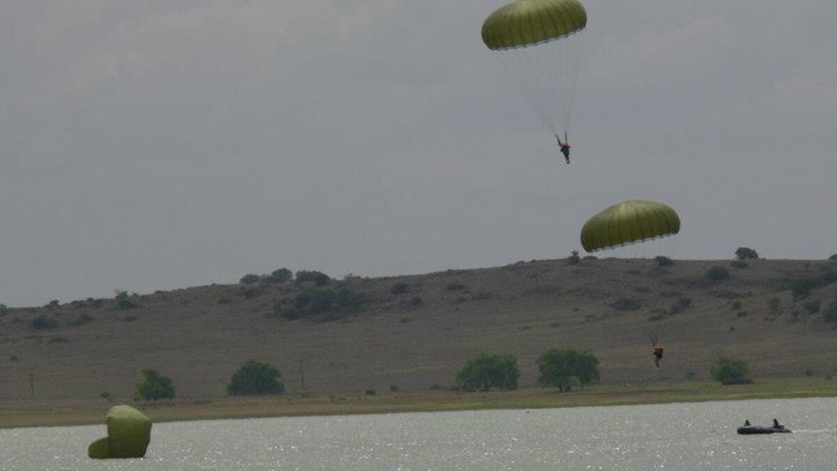 Parabats gracefully landing in a dam during a thrilling water jump, showcasing their precision and skill in aquatic parachuting maneuvers